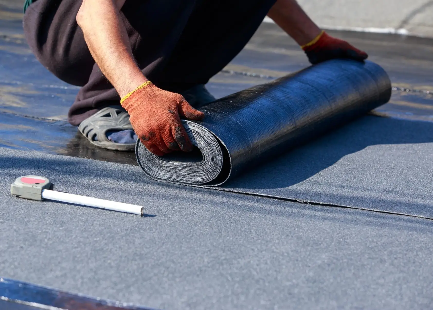 Artisan déroulant une membrane d'étanchéité sur une toiture-terrasse – entreprise Altitude, spécialiste étanchéité en Alsace